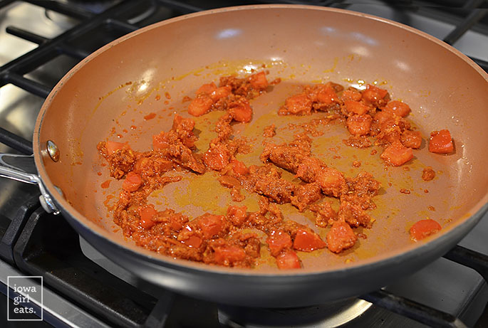 red curry paste and tomato in a skillet