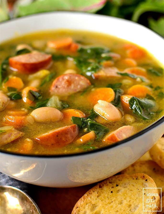 hearty soup with sausage, white beans, and spinach in a bowl