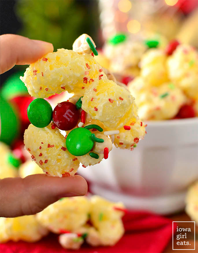 Hand holding a hunk of white chocolate puffcorn holiday mix