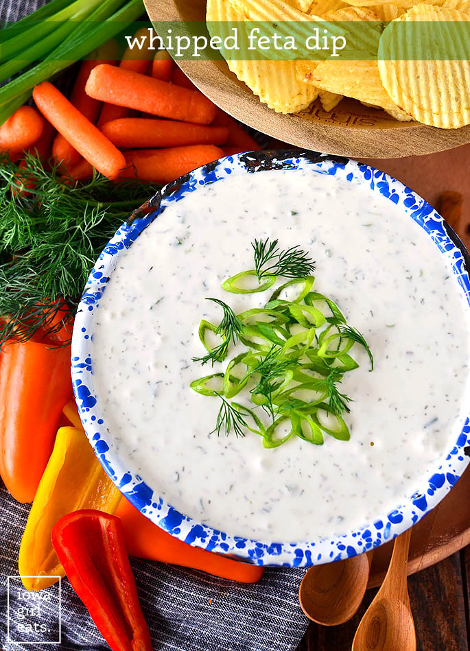 overhead photo of a bowl of whipped feta dip with green onions and dill on top