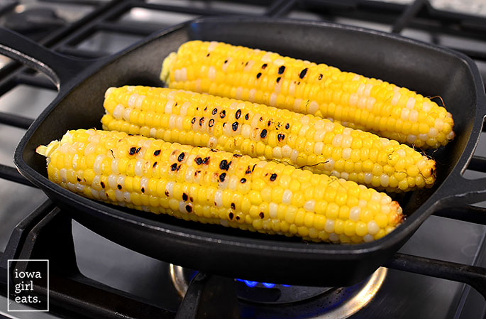 fresh sweet corn cooking in a grill pan