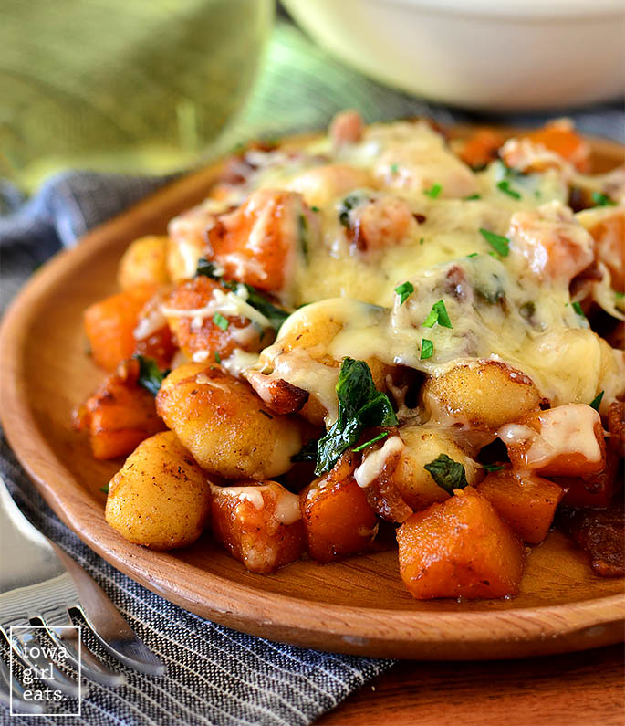 Scoop of Cheesy Bacon Butternut Squash Gnocchi Skillet on a wooden plate