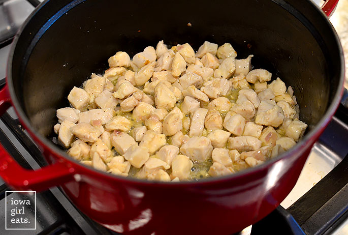 chopped chicken breasts sauting in a soup pot