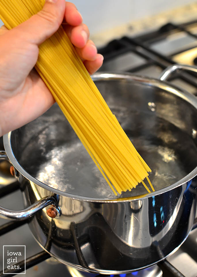 dry angel hair pasta being add to a pot of boiling water