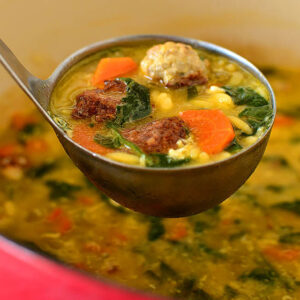 ladle scooping up homemade italian wedding soup from a soup pot