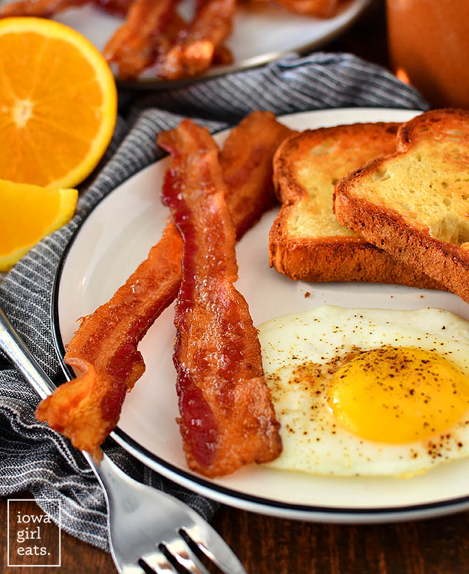 oven baked bacon slices on a plate with an egg and toast