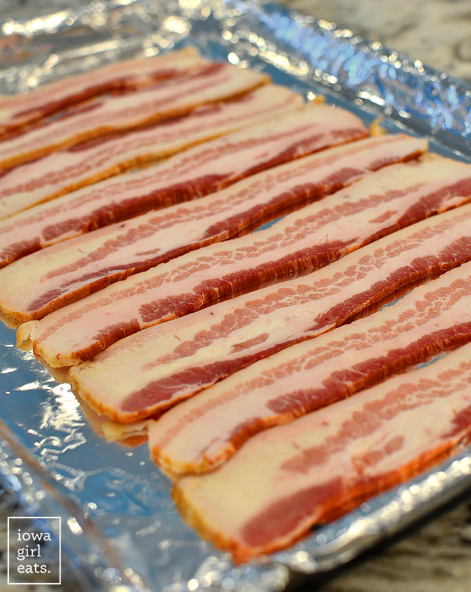 raw bacon slices on a baking sheet
