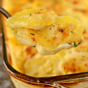 spoon scooping gluten free scalloped potatoes from a baking dish