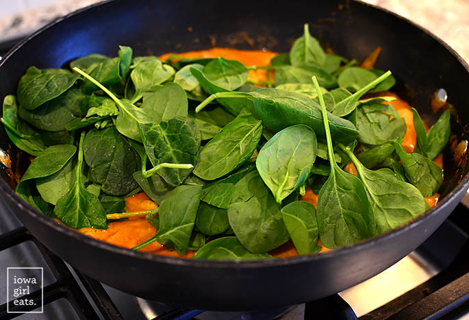 baby spinach being added to thai sweet potato curry