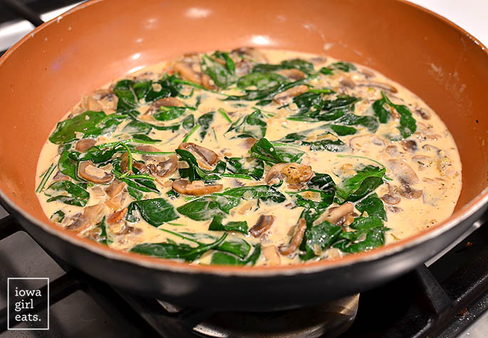 creamy spinach parmesan sauce simmering in a skillet