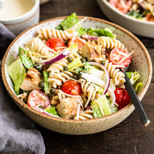 chicken caesar salad pasta in a bowl with a fork