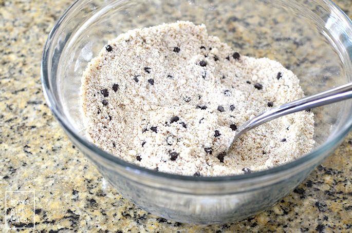 Dry cookie ingredients in glass mixing bowl with spoon