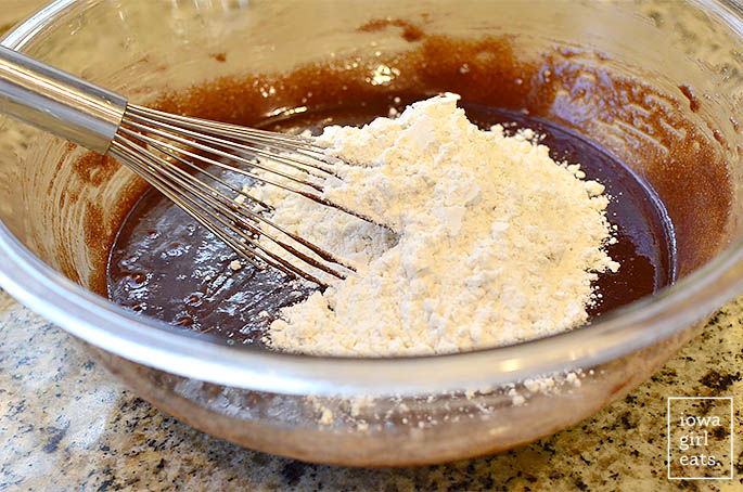 Bowl of brownie batter with flour being whisked in