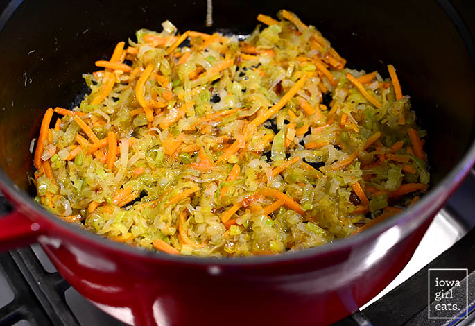 rodajas de puerros y zanahorias salteadas en mantequilla en un horno holandés