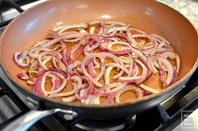 sliced red onions sauting in a skillet