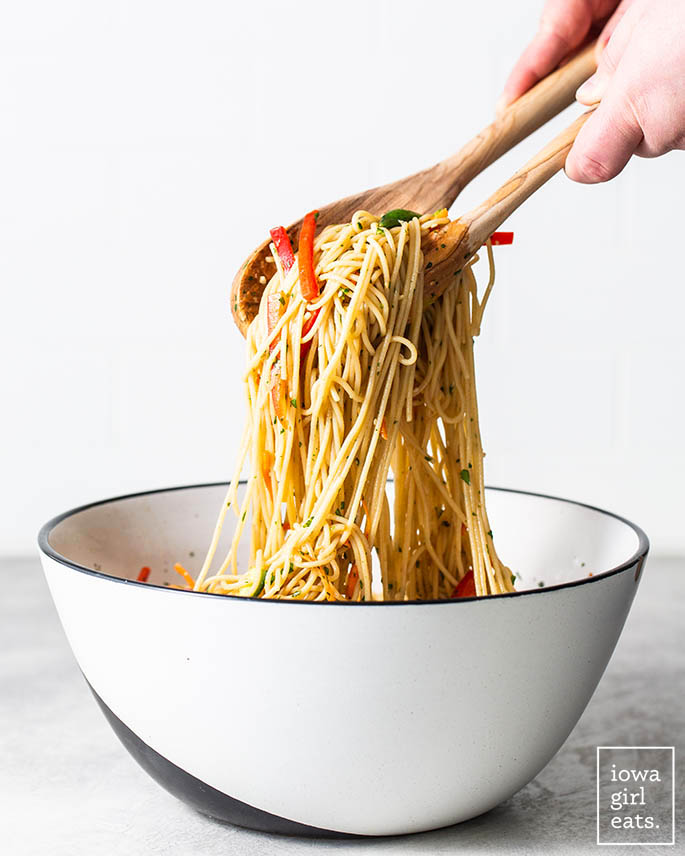 tongs pulling up cold sesame noodles from a bowl