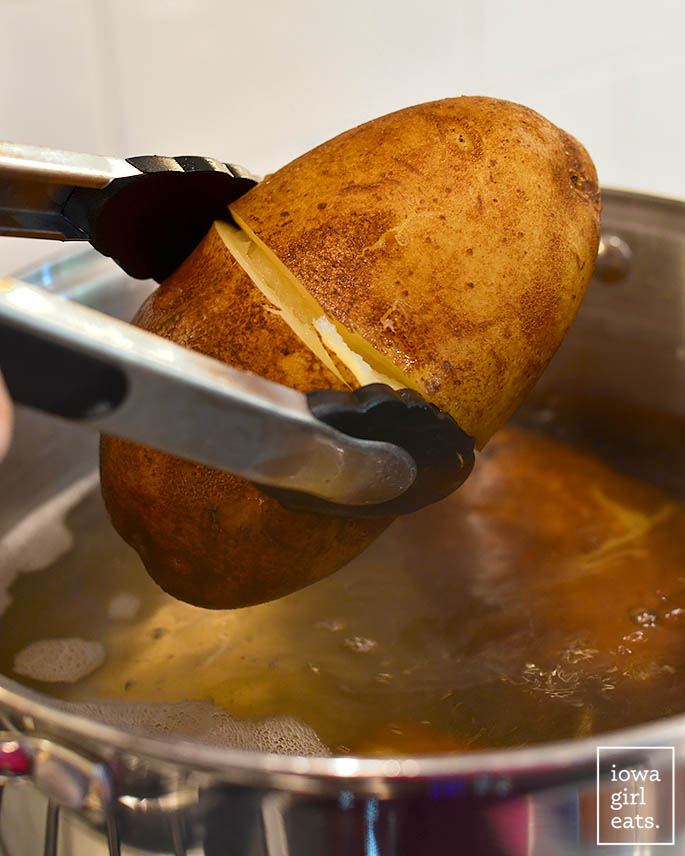 tongs holding a cooked potato
