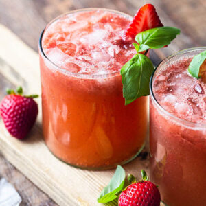 a strawberry basil ginger cocktail garnished with basil and strawberries