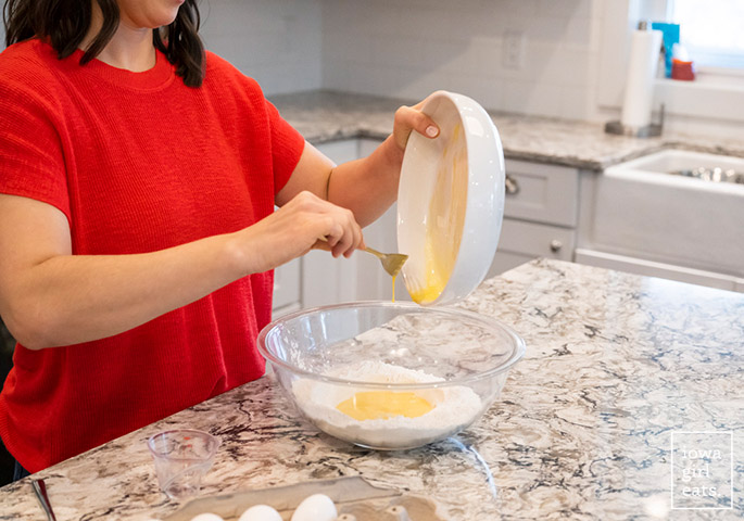 hand pouring eggs into gluten free flour
