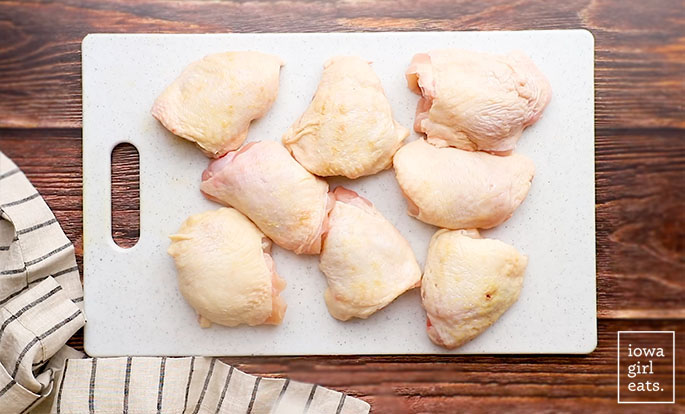 ، in skin on chicken thighs on a cutting board