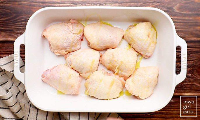 extra virgin olive oil drizzled over chicken thighs in a baking dish