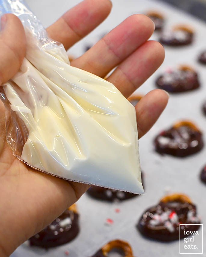 hand holding melted white chocolate in a piping bag