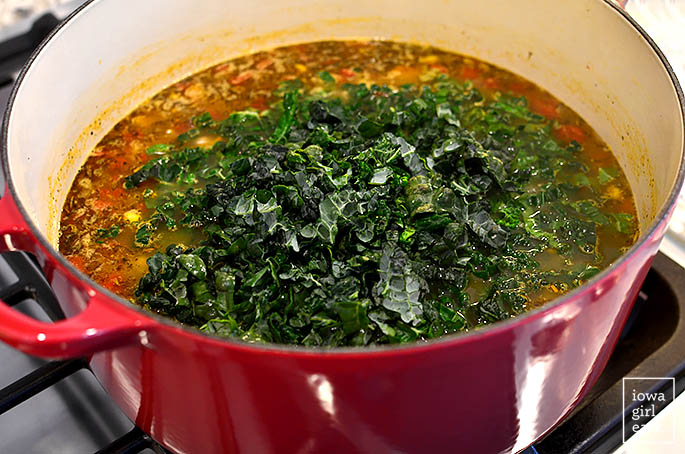 kale simmering inside a pot of vegetable soup