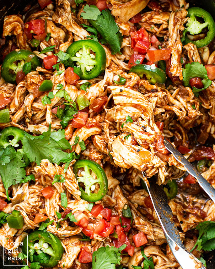tongs scooping up shredded mexican chicken
