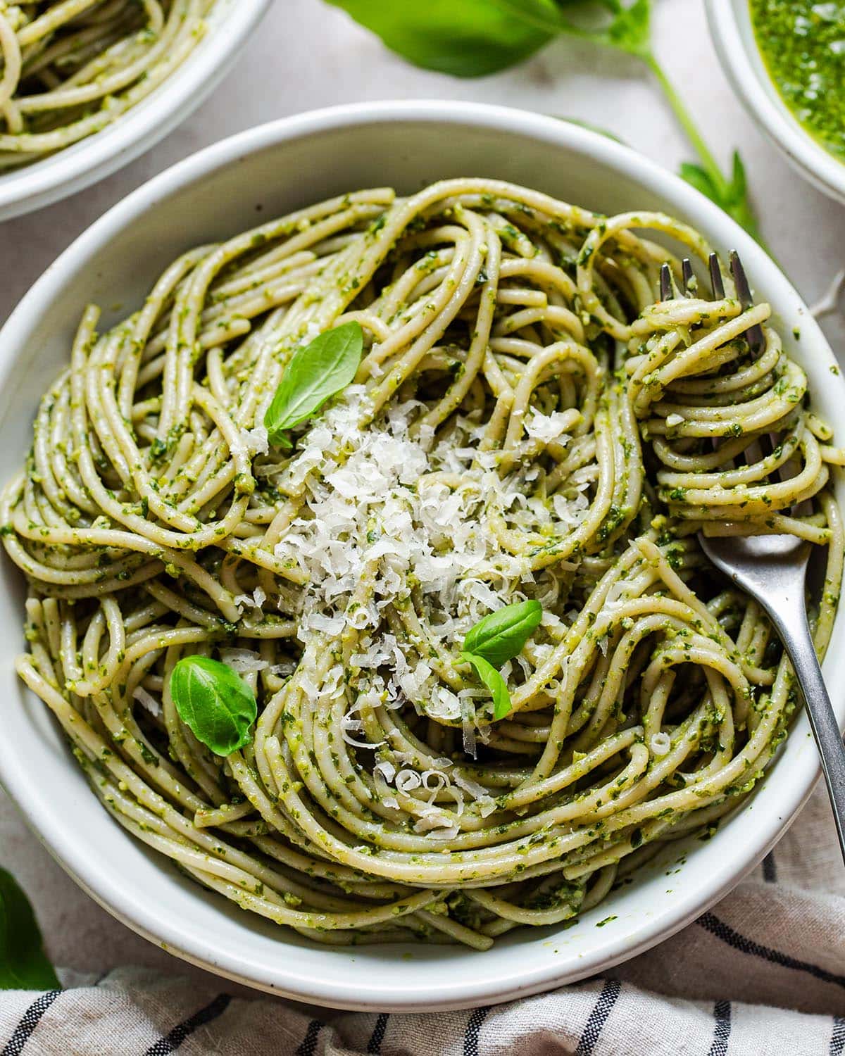 pesto pasta in a bowl with parmesan cheese