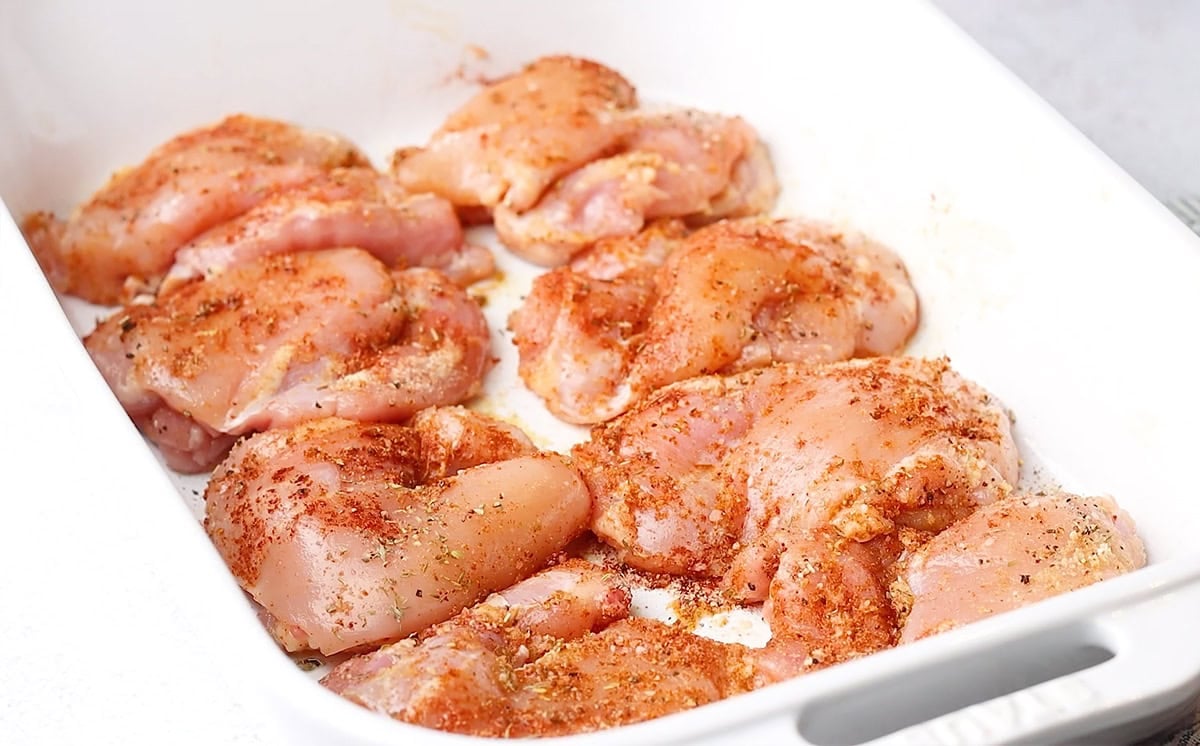 seasoned boneless chicken thighs in a baking pan